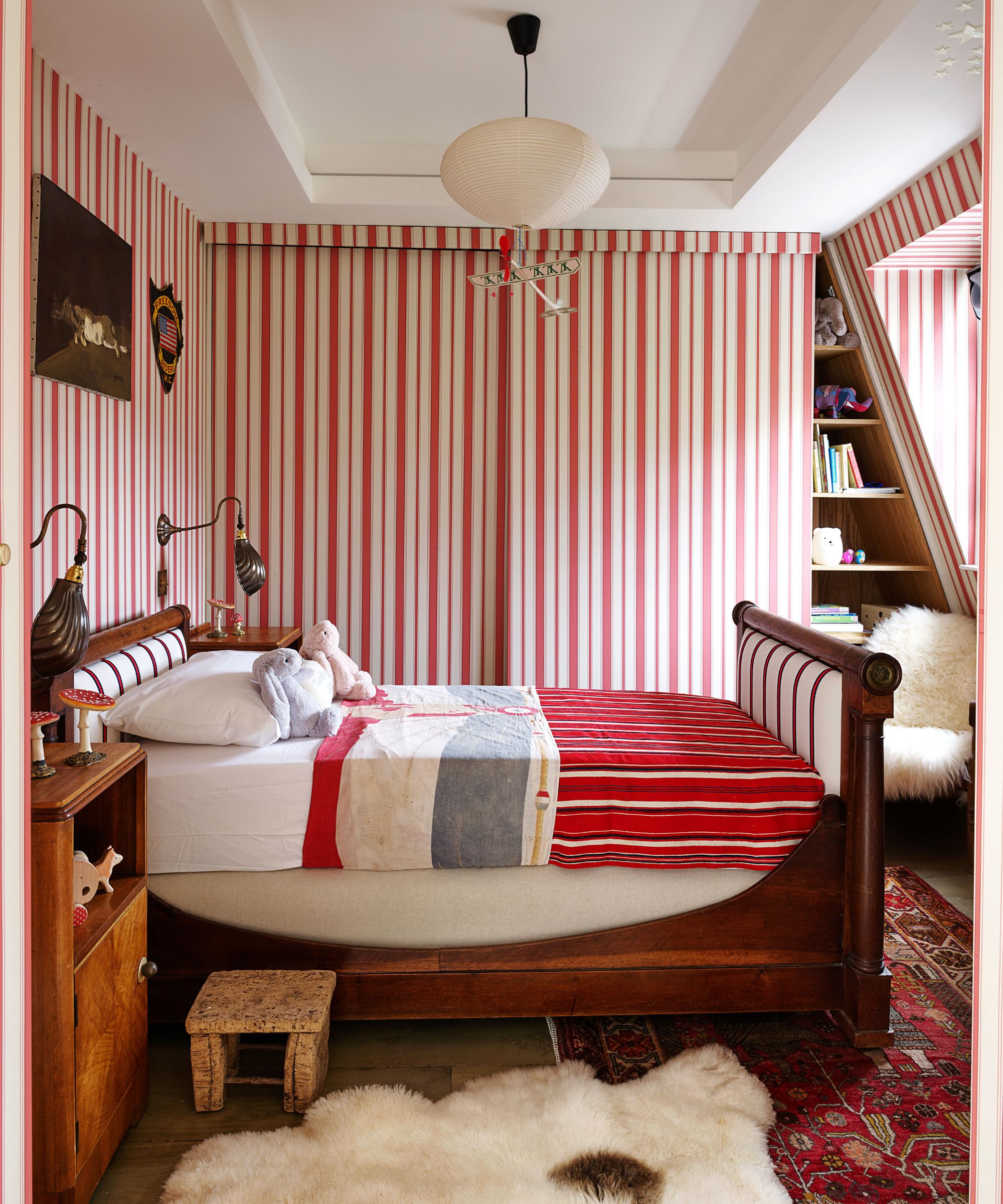 Red and white striped bedroom with vintage wood bed and sheepskin rug