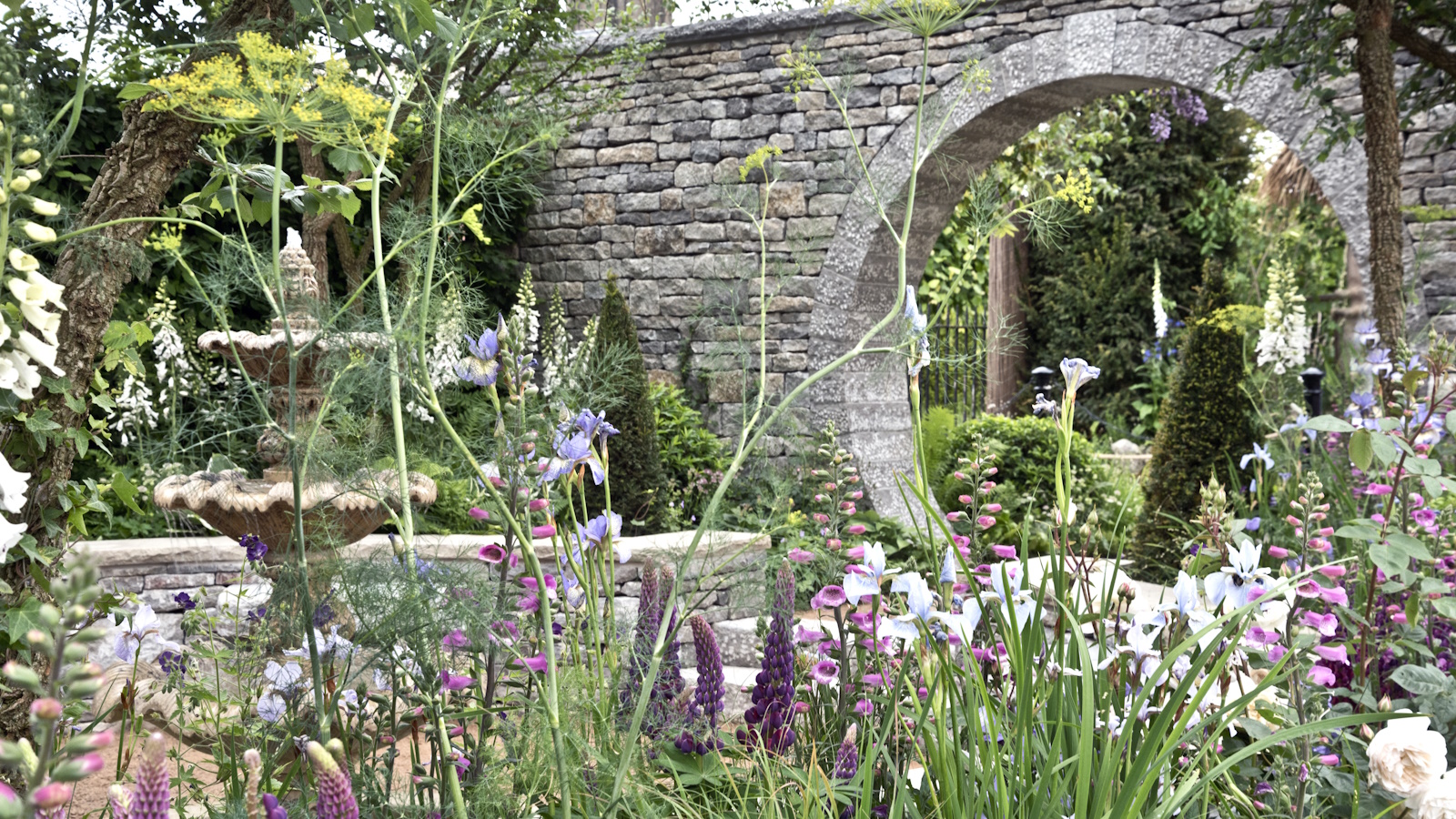 Naturalistic planting in front of stone moongate and fountain