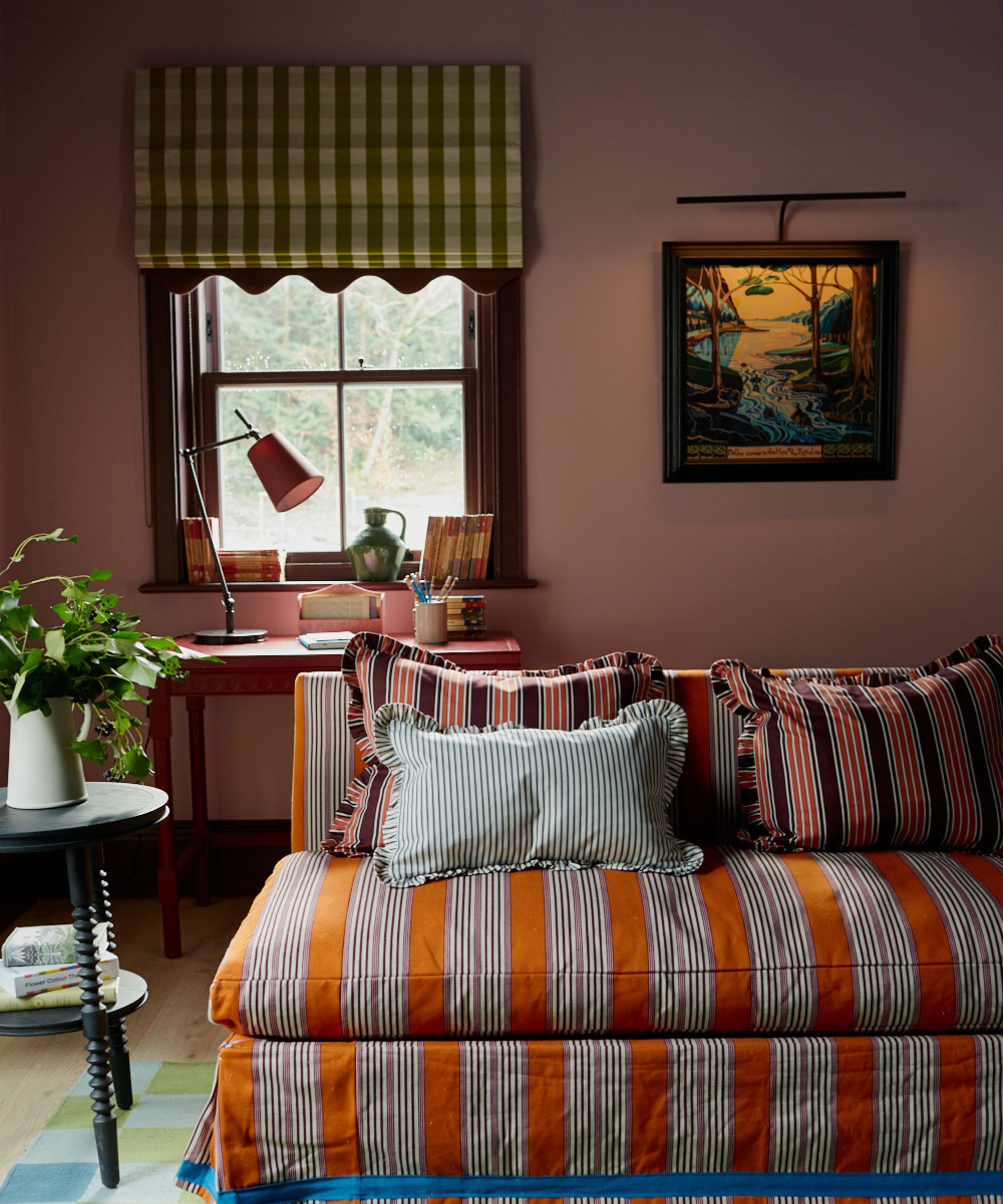 Colourful living room with pink walls, orange striped sofa, gingham blinds