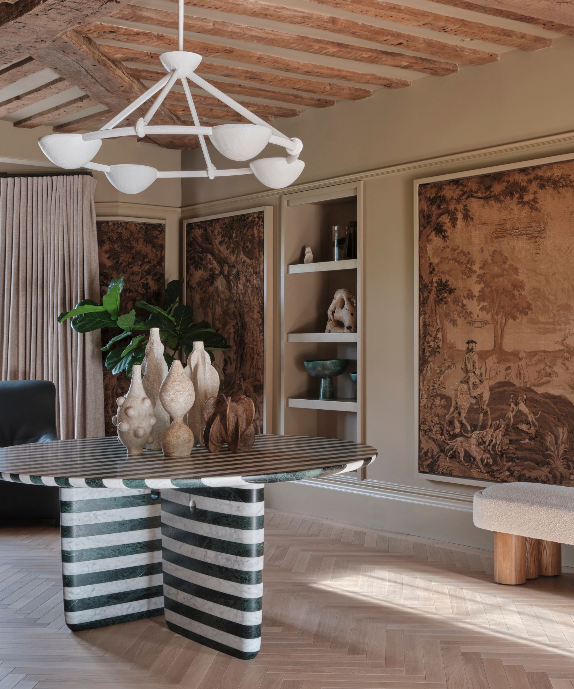 Hallway with beams, tapesty hanging, shelves of vases and stiped marble table